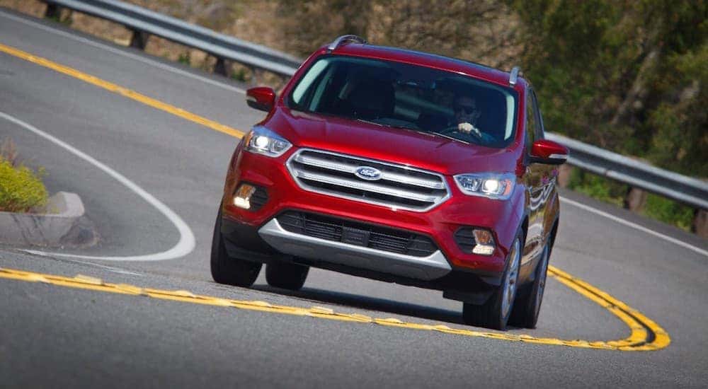 A red 2017 Ford Escape is driving around a sharp corner after leaving a used car dealership near me in Paris, KY.