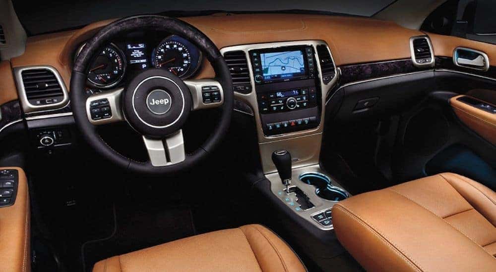 The tan and black interior is shown on a 2016 used Jeep Grand Cherokee.