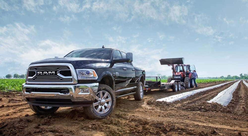 A blue 2018 Ram 2500 HD is being used to tow a tractor trailer.