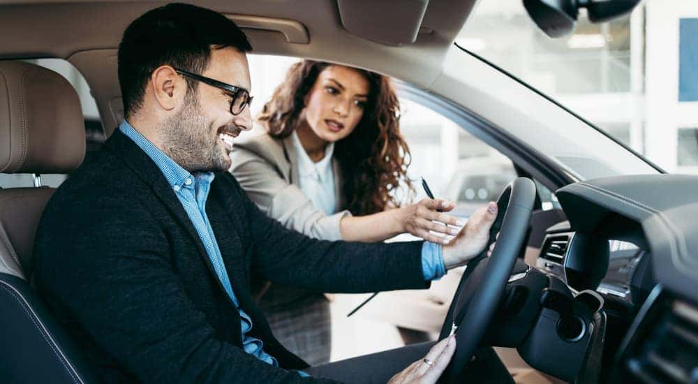 A saleswoman is talking to a man sitting in a car at a Lexington, KY, dealership.