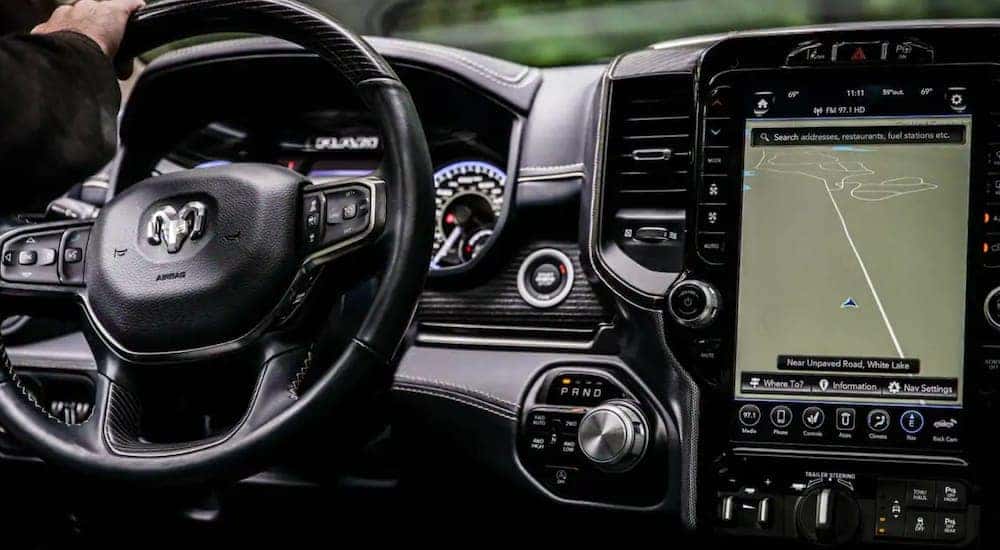 The interior of a 2021 Ram 1500 shows the steering wheel and infotainment screen.