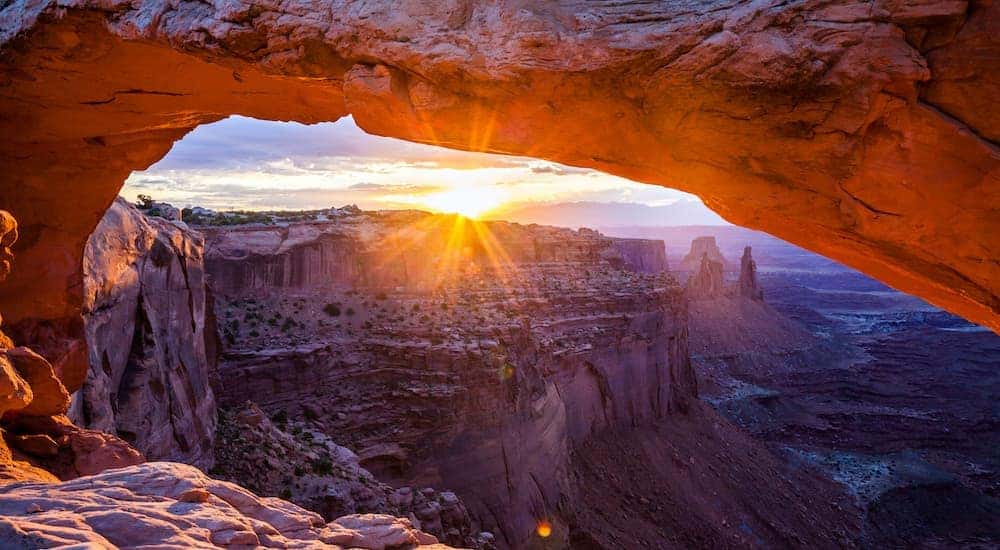 The sun is shown setting over rock formations in the Moab Desert.
