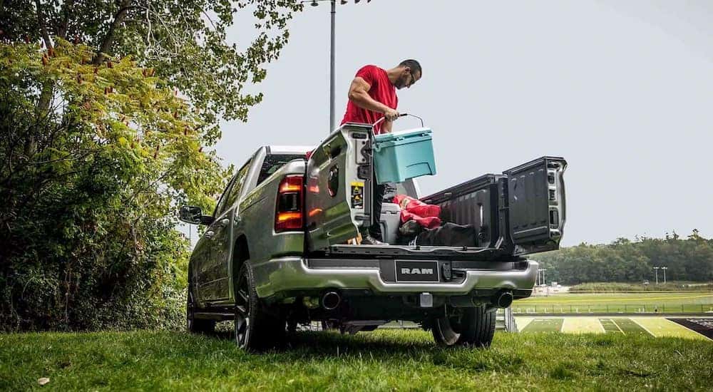 A person unloading gear from the bed of a grey 2024 Ram 1500.