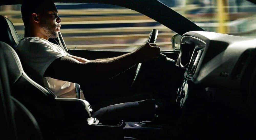 A man is shown from the side driving a 2021 Dodge Charger.