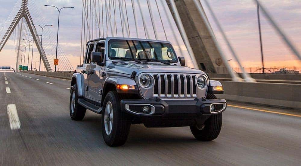 A silver 2021 Jeep Wrangler is shown from the front driving over a cable bridge after leaving a Lexington Jeep dealer.