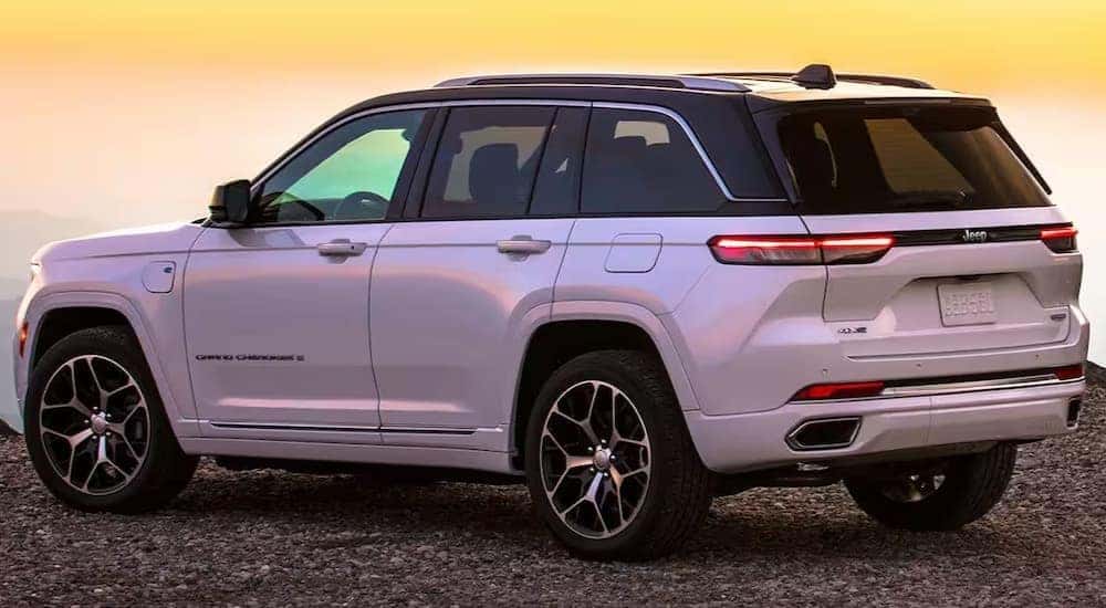A white 2024 Jeep Grand Cherokee 4xe is shown parked off-road.