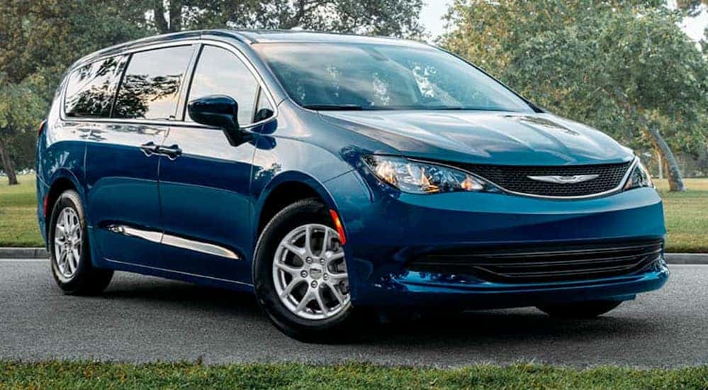 A blue 2020 Chrysler Voyager is parked in front of trees after leaving a used Chrysler dealer in Lexington.