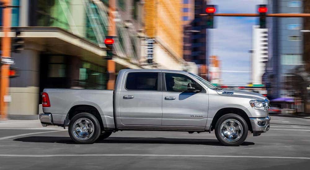 A silver 2019 Ram 1500 is driving on a city street.