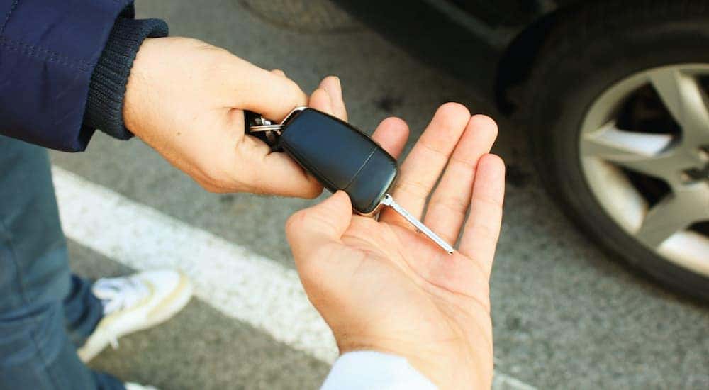 A salesman is passing a set of keys at a Kentucky used car lot.