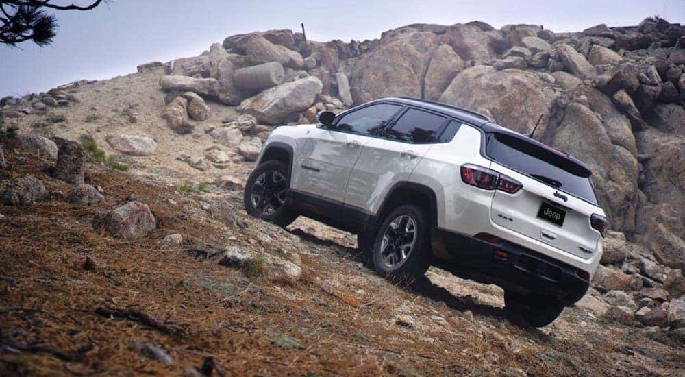 A white 2020 Jeep Compass Trailhawk is climbing a rocky hill near Lexington, KY.
