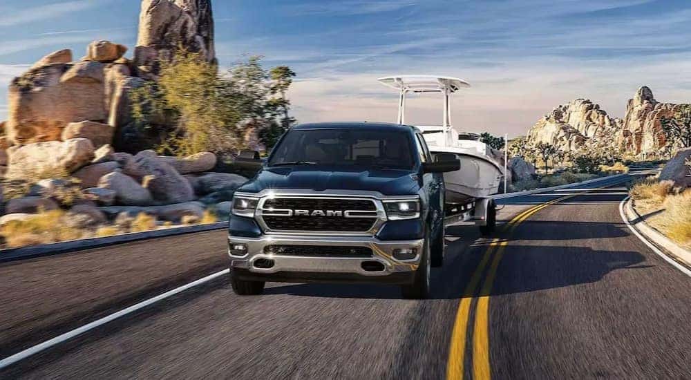 A blue 2023 Ram 1500 Big Horn is shown towing a boat to a Ram dealer near Maysville.