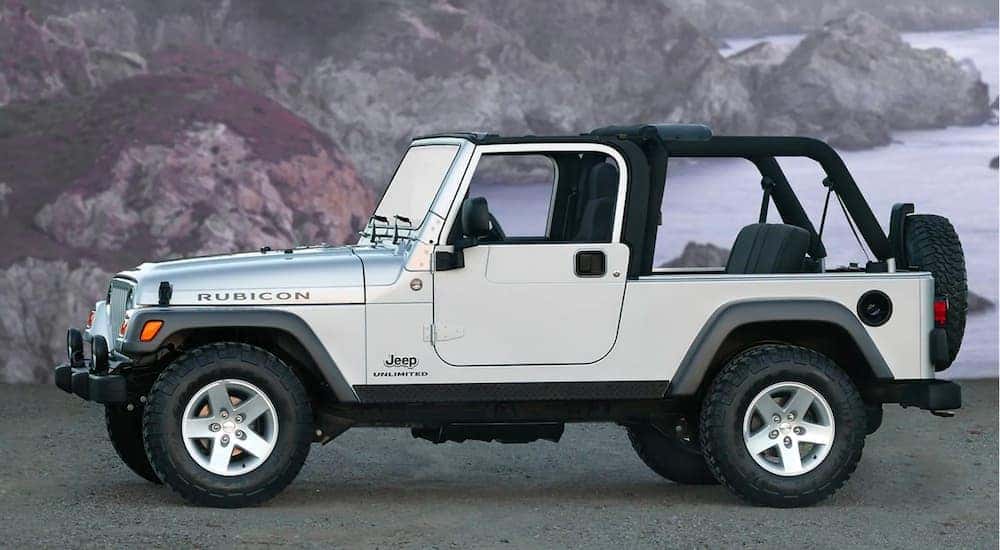 A silver 2005 used Jeep Wrangler Rubicon Unlimited is shown from the side with no roof and a bay in the background.