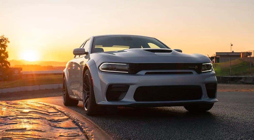 A silver 2021 Dodge Charger is driving on a track at dusk after leaving a Lexington Dodge dealer.