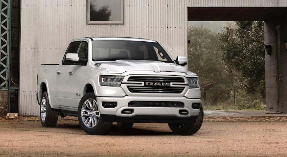 A white 2020 Ram 1500 is shown from the front parked in front of a barn.
