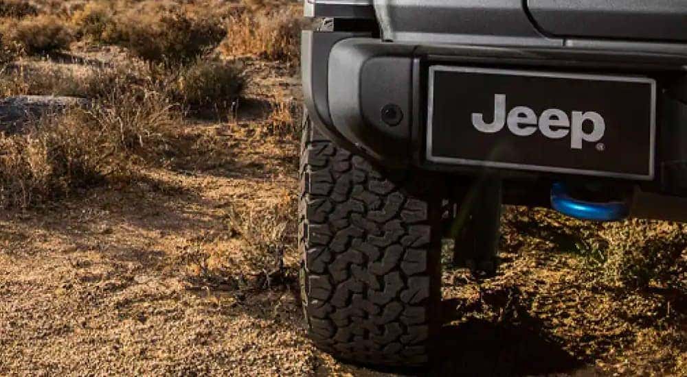 A close up shows the rear tire of a Jeep parked in the dirt after leaving a Jeep Wrangler dealer.