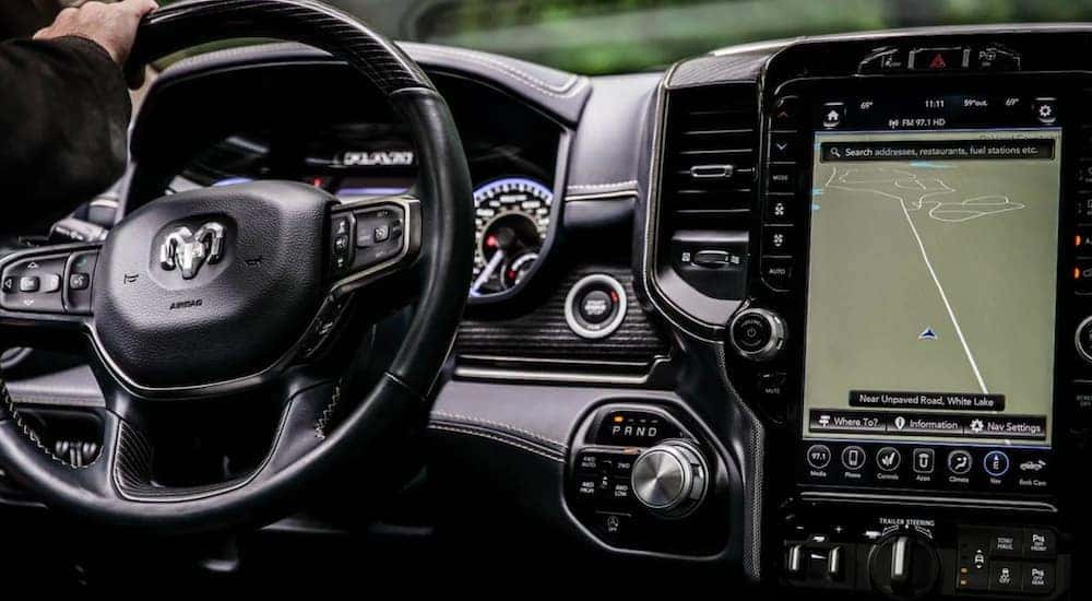 The interior of a 2021 Ram 1500 shows the steering wheel and infotainment screen.