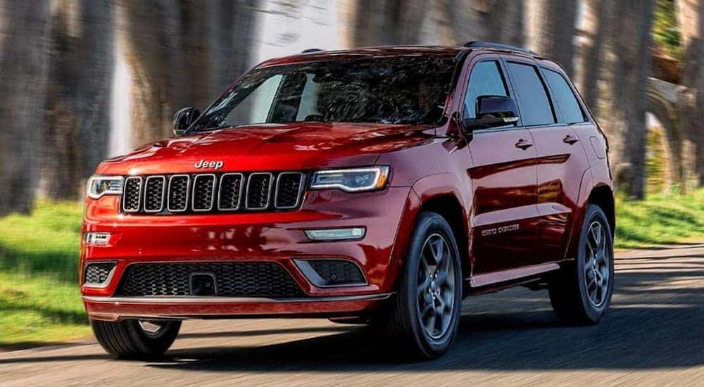 A red 2020 Jeep Grand Cherokee is shown driving through a city.