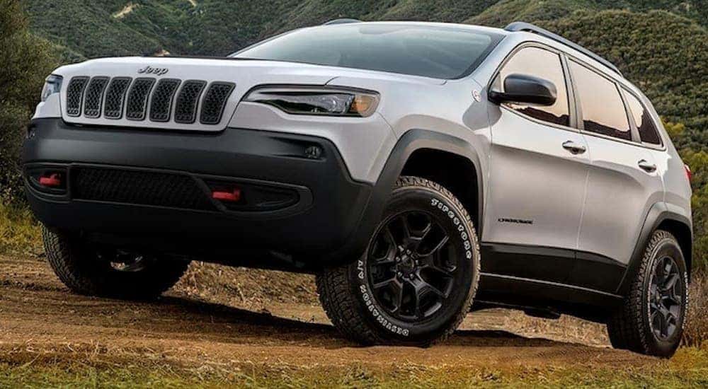 A white 2019 used Jeep Cherokee is driving through a field after leaving a used SUV dealer in KY.