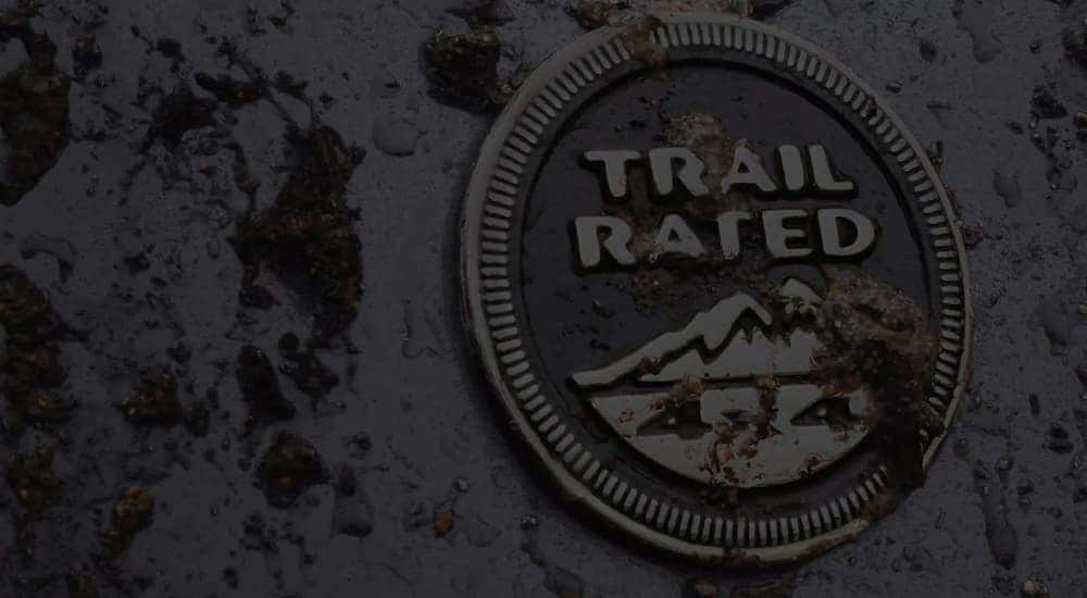 A close up shows a Jeep trail rated badge covered in dirt.