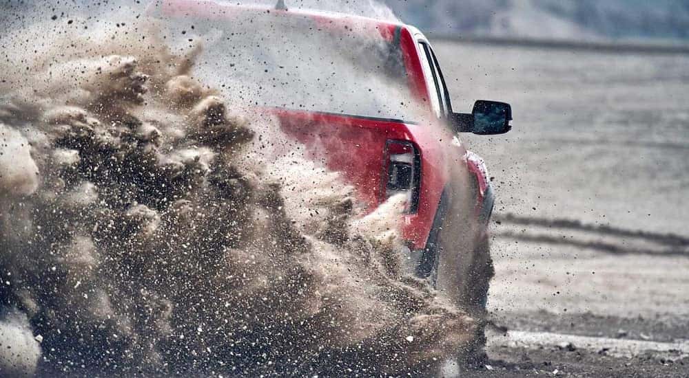 A close up shows the rear end of a red 2021 Ram 1500 TRX kicking up dirt after leaving a Lexington Ram dealer.
