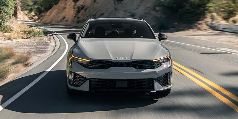 Kia sedan driving on winding road