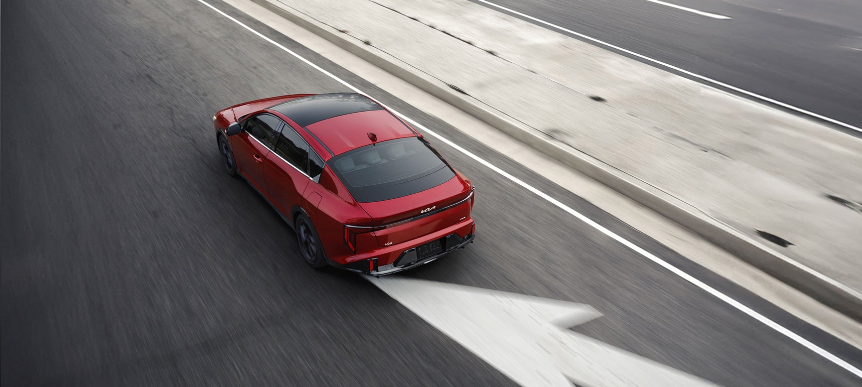 Red Kia sedan driving on the road