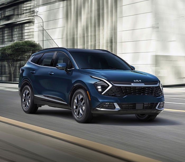 A blue Kia Sportage SUV driving through a city street, showcasing its modern design and bold front grille