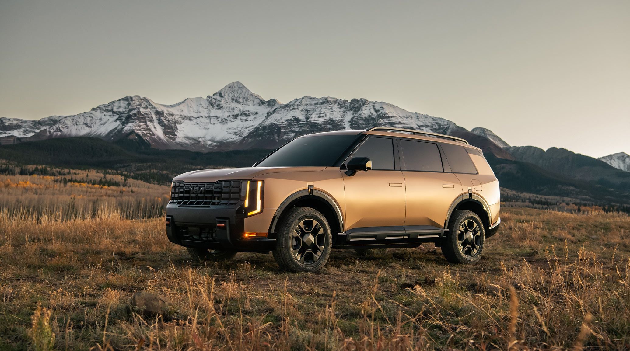 A Kia Telluride SUV parked in a scenic mountainous landscape during sunset.