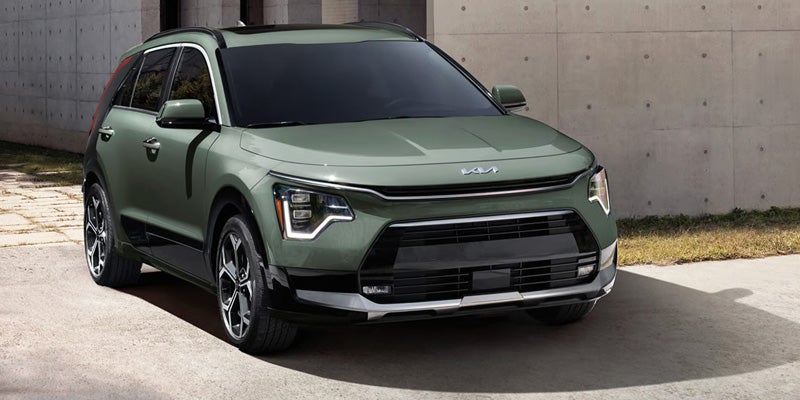 Green Kia SUV parked outdoors near concrete wall