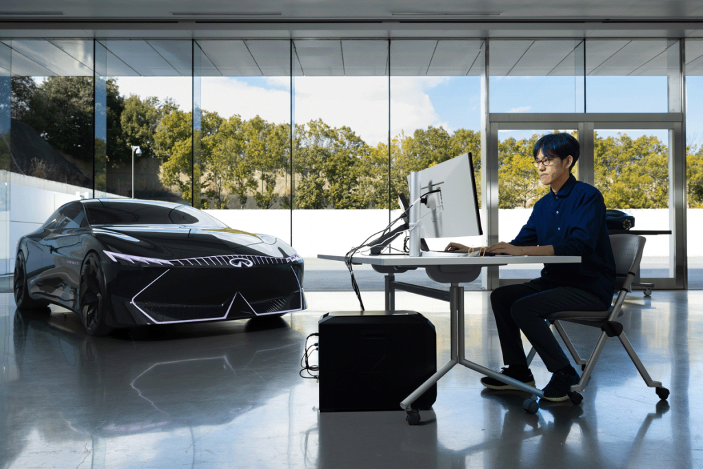 man working on his computer next to an Infiniti