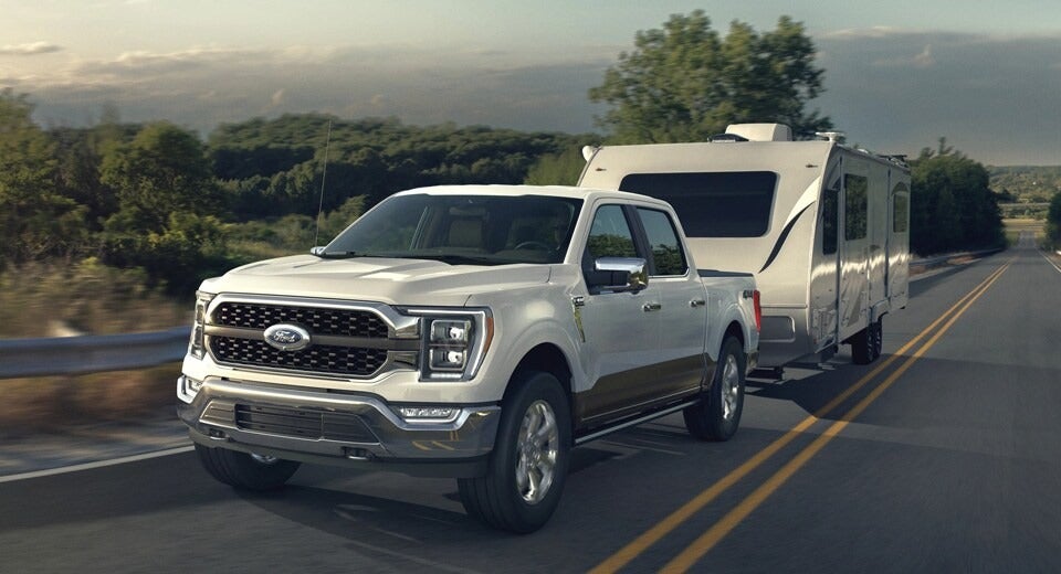 white Ford F-150 pulling a trailer on rural highway