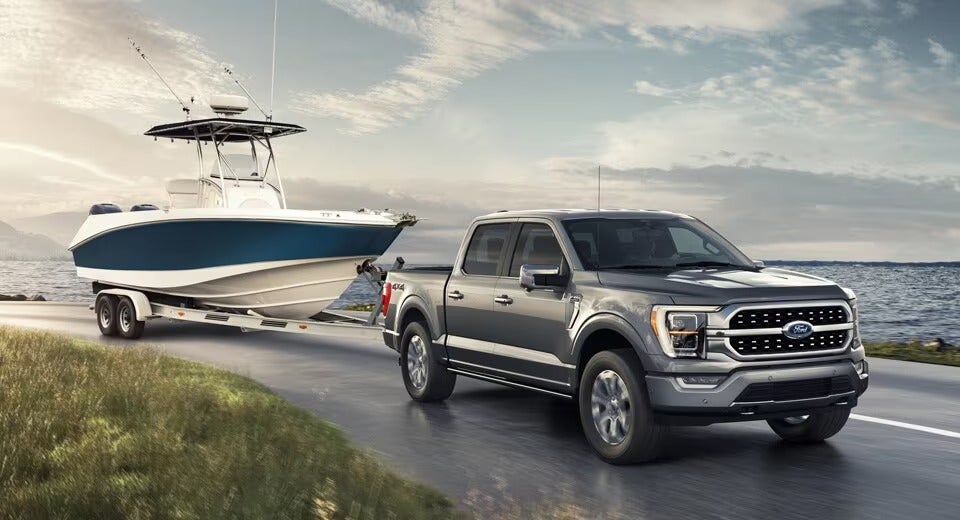 Ford F-150 pulling a boat on a trailer along the ocean shore
