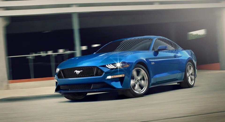 blue Mustang driving out of a parking garage with headlights on