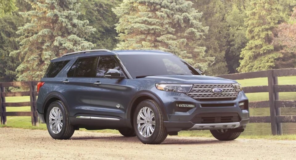 dark blue Ford Explorer parked on dirt road in front of fence and pasture