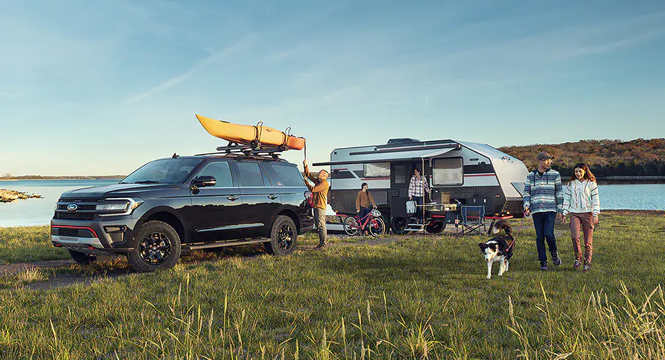 ford explorer and trailer parked for camping in front of lake