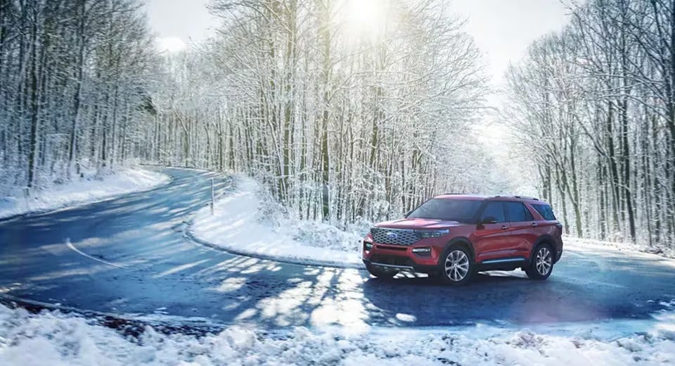 red Ford Explorer going up windy road in winter time