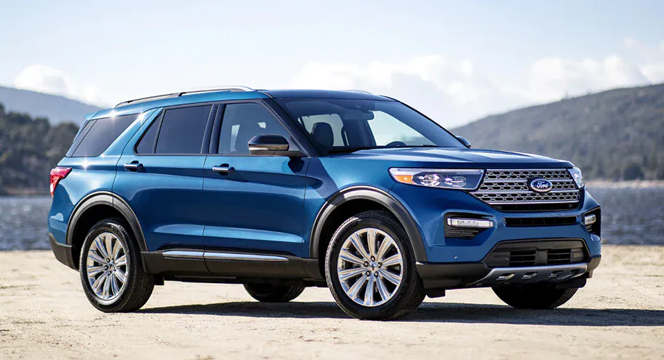 blue Ford Explorer parked in front of a lake in summer