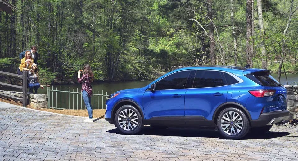 compact blue Ford parked a scenic spot with a family taking a photo