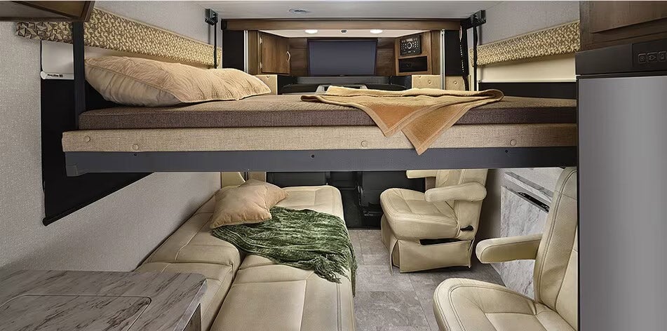 RV interior with bunk beds, leather seats, neutral tones, overhead TV, modern camper van sleeping area and living space