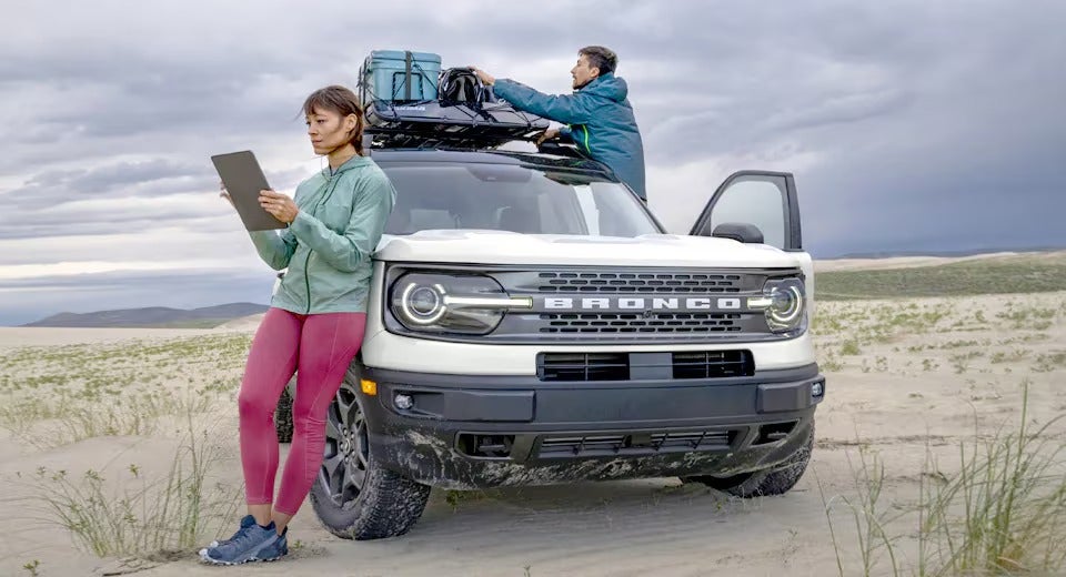 couple getting gear off the roof of their Ford Bronco while at the beach