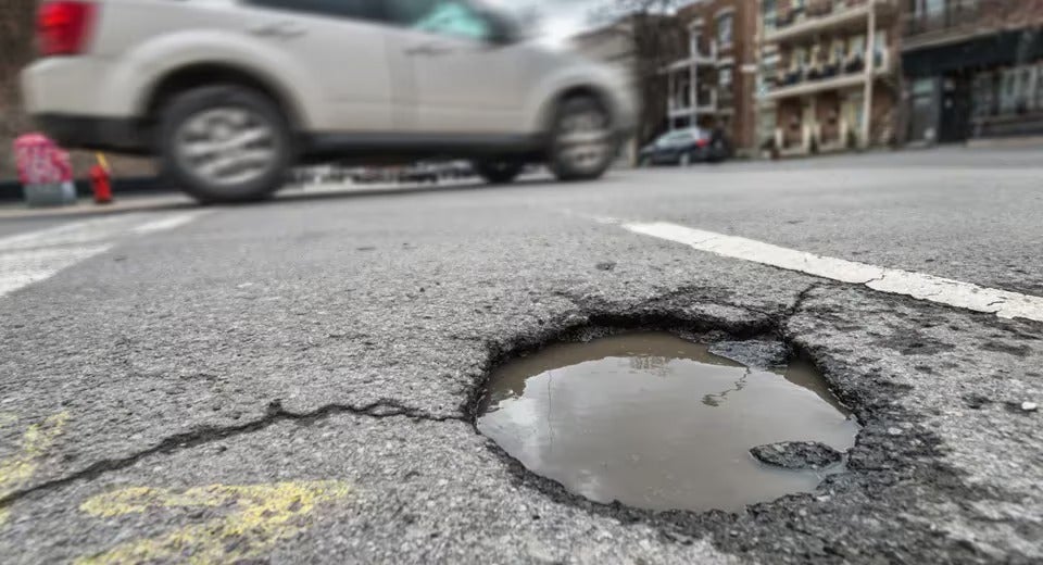 closeup of a pothole on a busy street

