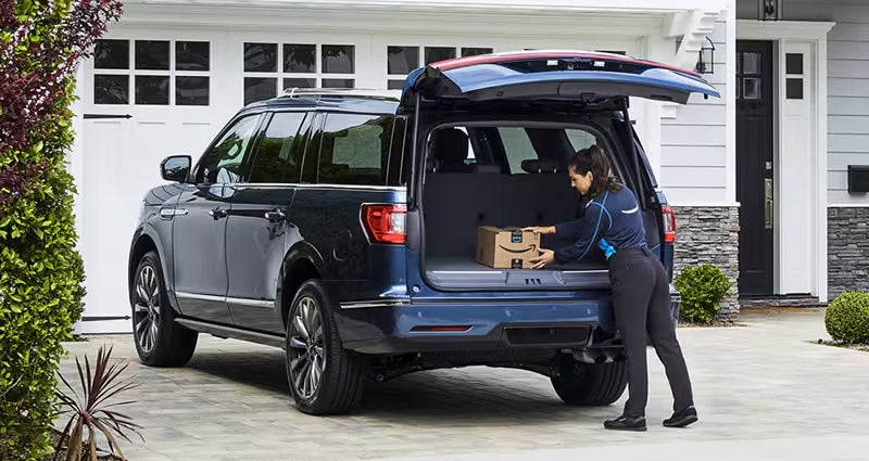 Ford Expedition delivery scene with Amazon package, rear cargo area open, delivery person loading box