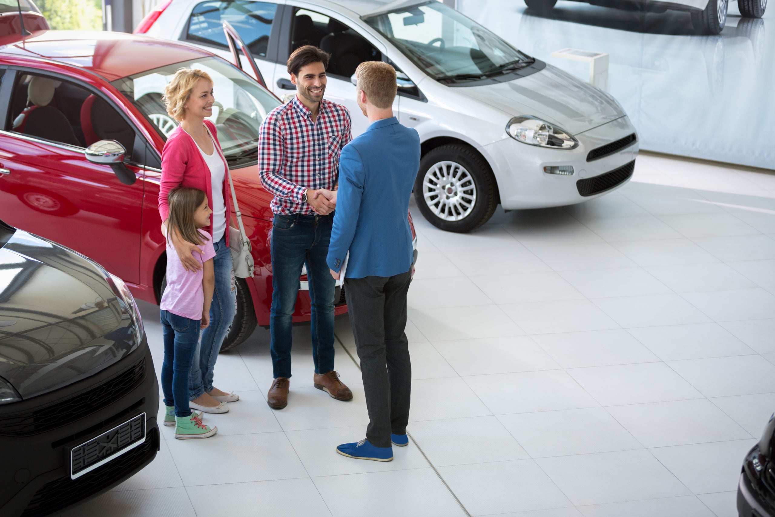 Family viewing vehicles with a salesperson in a showroom.