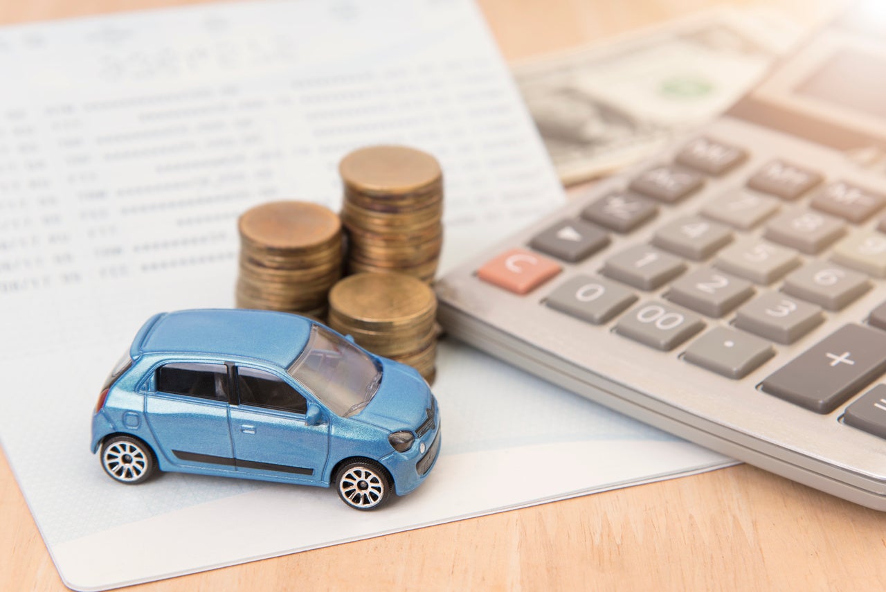 car with calculator and money on wood table. insurance concept.