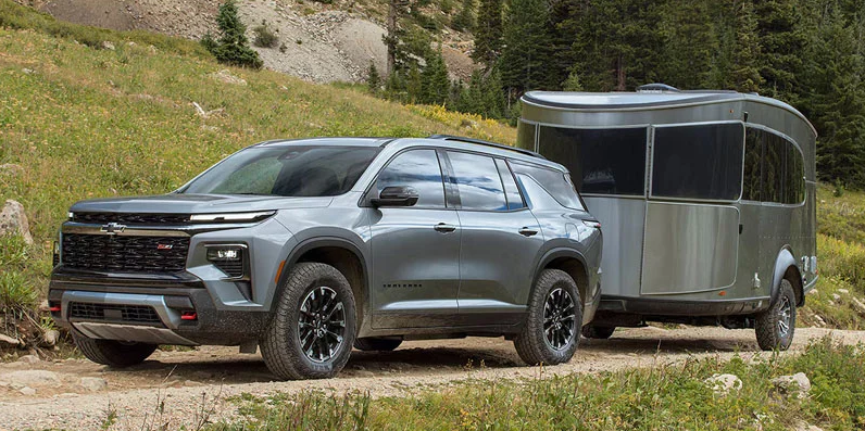 A 2026 Chevrolet Traverse towing a trailer down a dirt road.