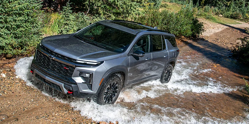 A 2026 Chevy Traverse off-roading through a stream of water.