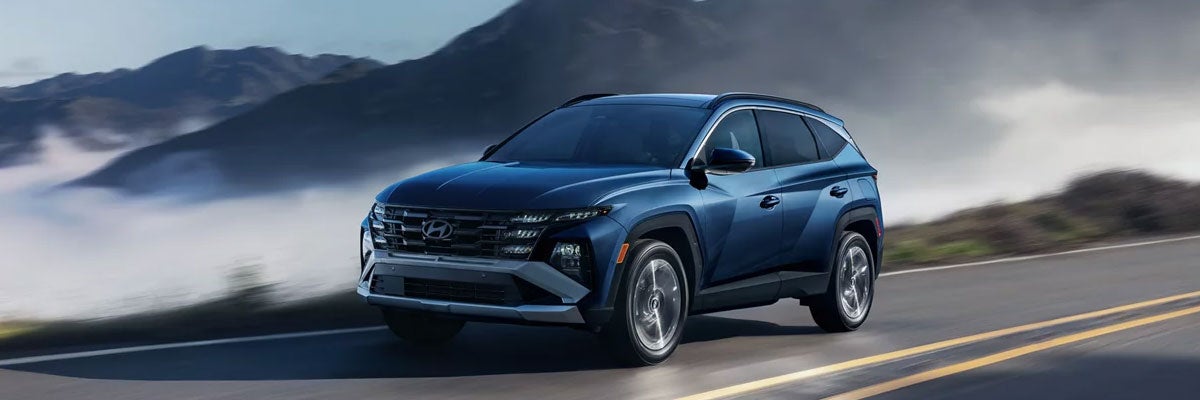 Blue 2026 Hyundai Tucson Driving on a Fall Day