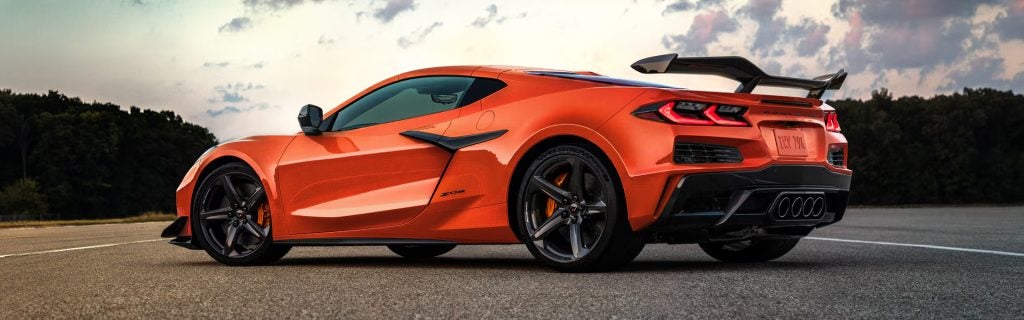Orange Chevrolet Corvette sports car parked on a track at sunset.