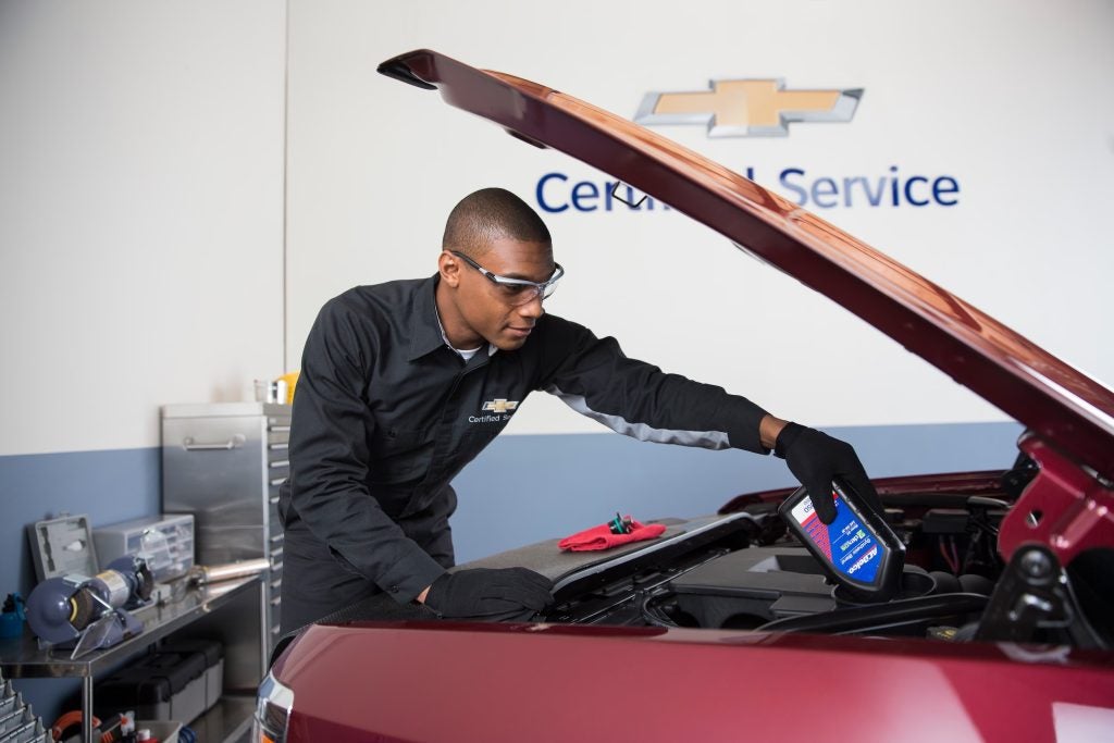 technician pouring oil into a Chevrolet engine
