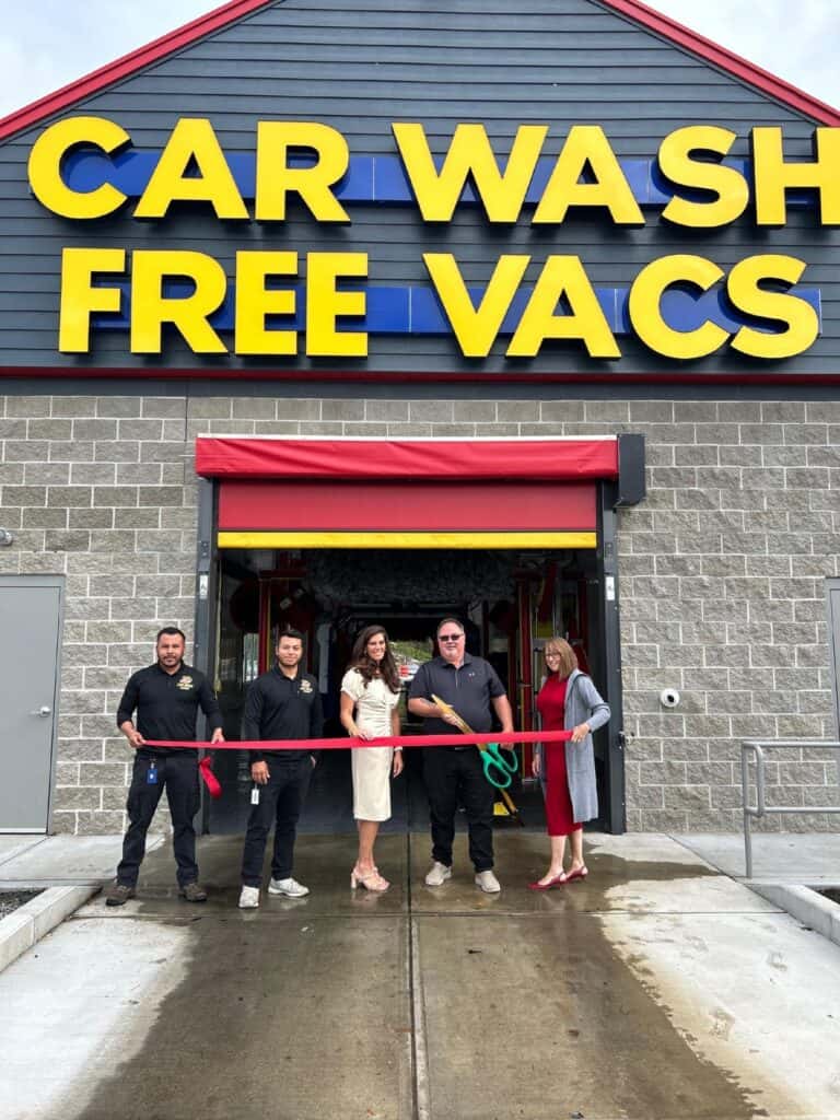 A group of people stands in front of a car wash, showcasing the free vacuum service available.